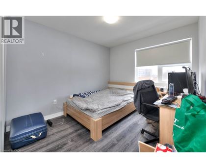 A bedroom with a bed, desk, chair, and a window with blinds.
