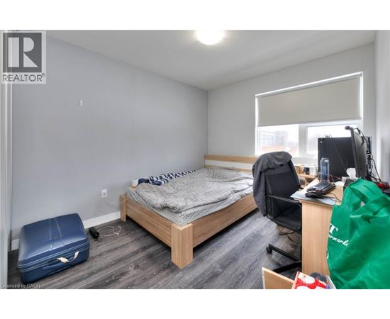 A bedroom with a bed, desk, chair, and a window with blinds.