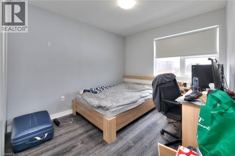 A bedroom with a bed, desk, chair, and a window with blinds.