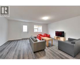 A living room with a grey couch, red chairs, and a wooden table.