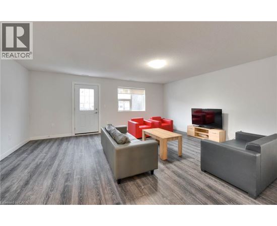 A living room with a grey couch, red chairs, and a wooden table.