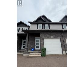 A house with a grey and black exterior and a white garage door.