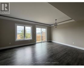 A spacious room with wooden floors and a large window overlooking a fence.
