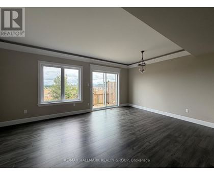 A spacious room with wooden floors and a large window overlooking a fence.