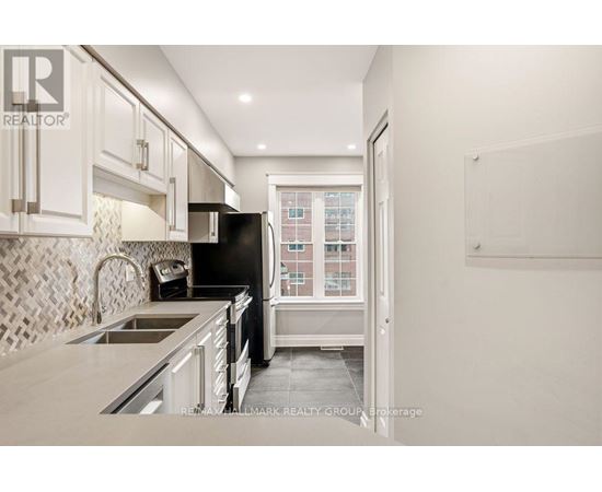 A kitchen with a black refrigerator and white cabinets.