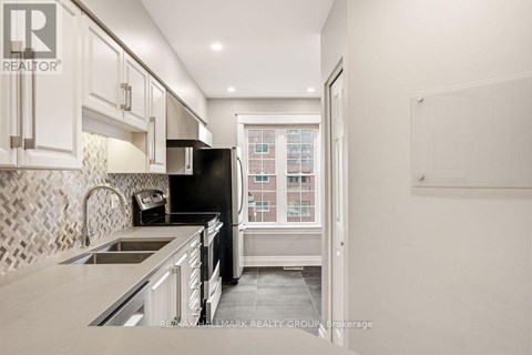A kitchen with a black refrigerator and white cabinets.