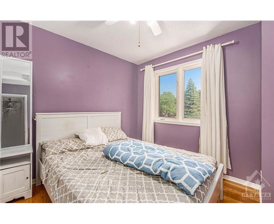 A bedroom with purple walls and a large bed with a blue and white comforter.