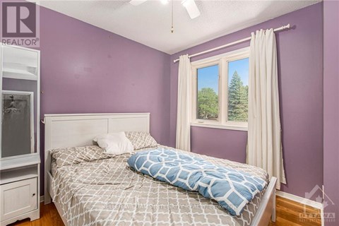 A bedroom with purple walls and a large bed with a blue and white comforter.
