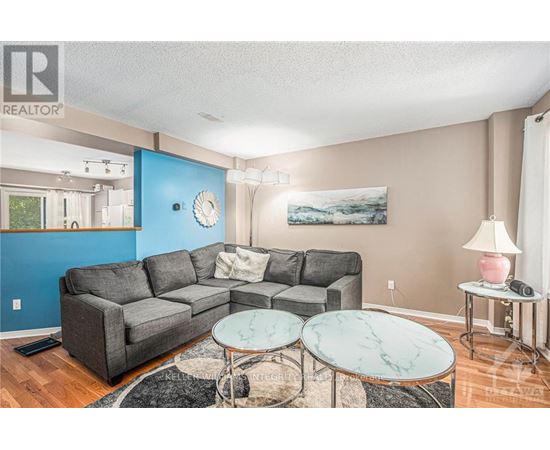 A living room with a grey couch, a marble table, and a painting on the wall.