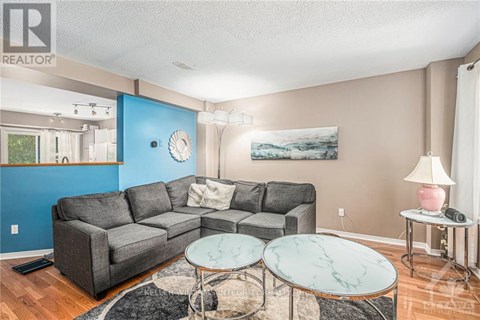 A living room with a grey couch, a marble table, and a painting on the wall.