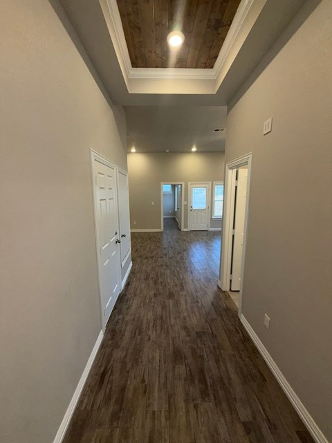 A long hallway with wood floors and white walls.