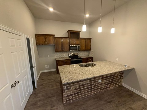 A kitchen with a brick counter and wooden cabinets.