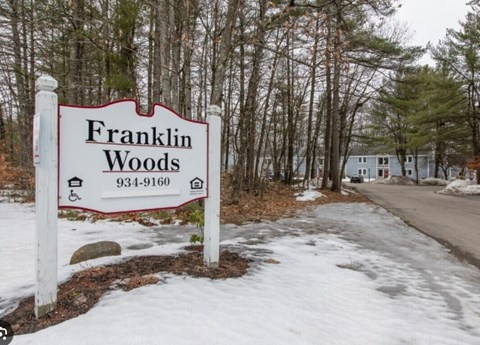 A sign for Franklin Woods with a phone number on it.