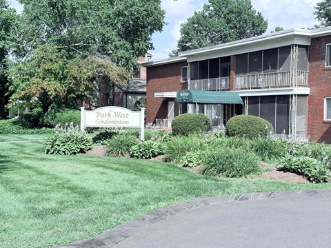 A sign for Park West Condominium stands in front of a brick building.