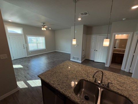 A kitchen with a granite countertop and a stainless steel sink.