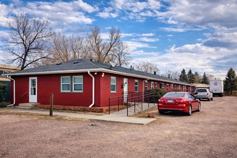 A red house with a car parked in front.