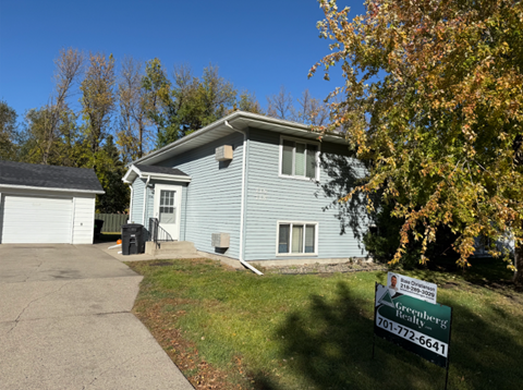 A blue house with a sign in front that says Greenberg Realty.