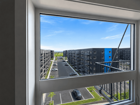 A view from a window looking out at a street lined with parked cars and buildings.