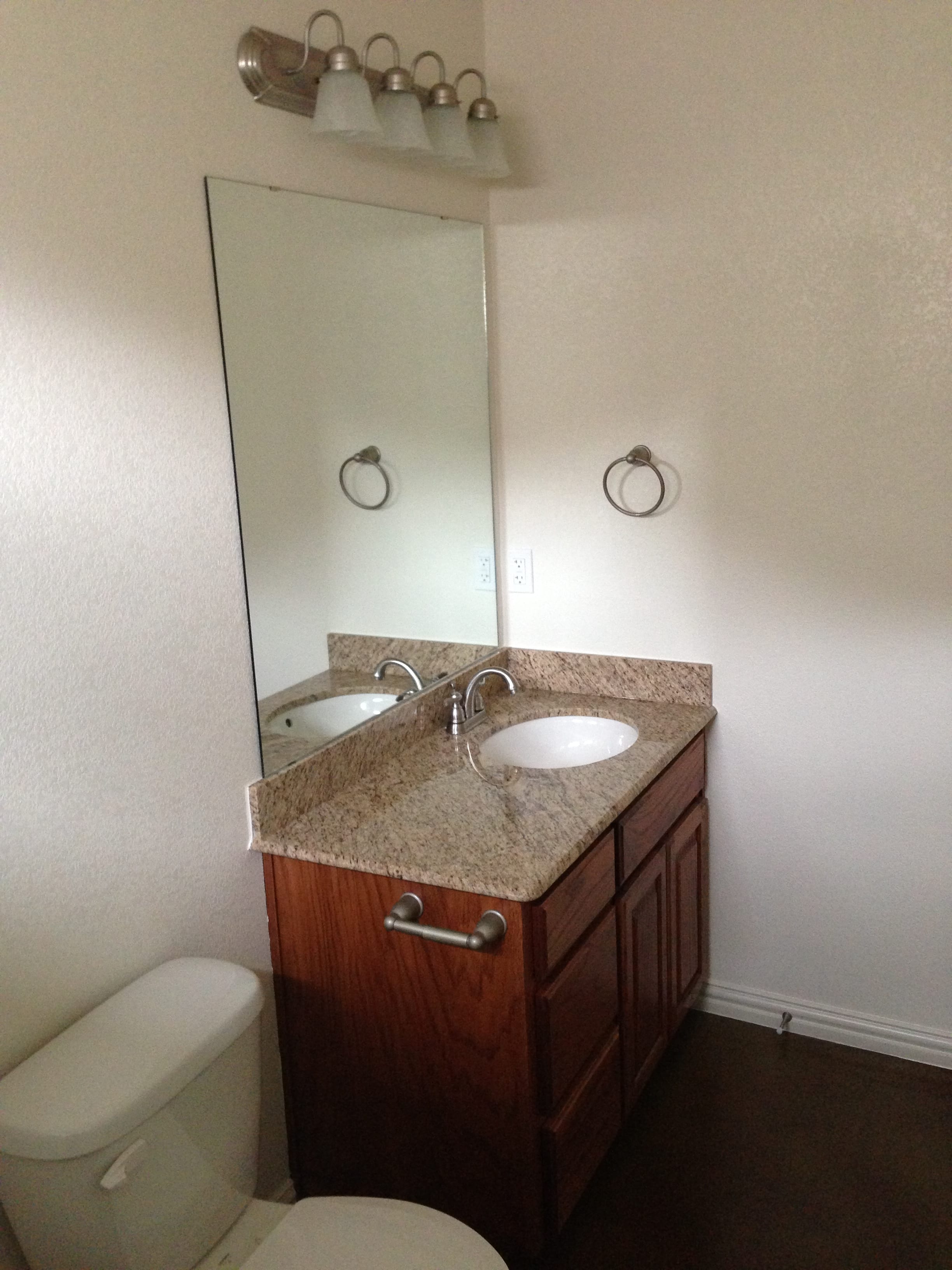 A bathroom with a toilet, sink and mirror.