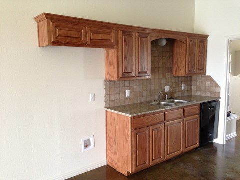 A kitchen with brown cabinets and a black dishwasher.