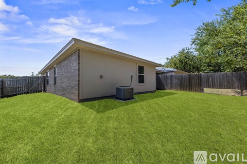 A house with a fence and a trash bin in front.