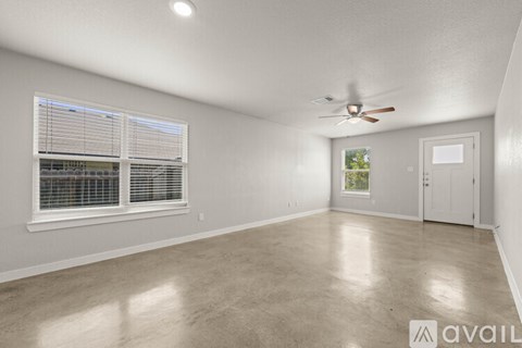 A spacious room with a ceiling fan and a window with blinds.