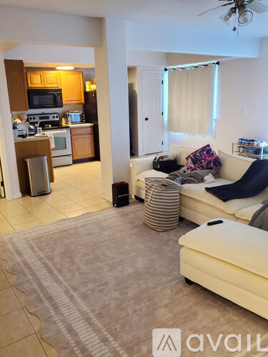 A living room with a couch and a kitchen area in the background.