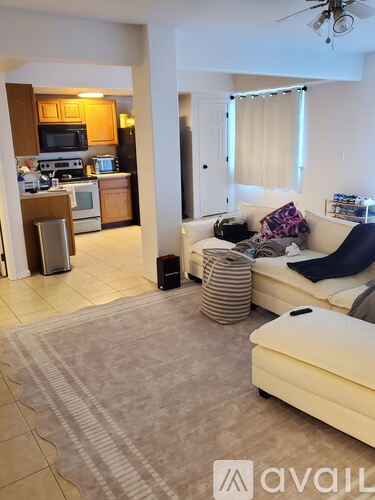 A living room with a couch and a kitchen area in the background.