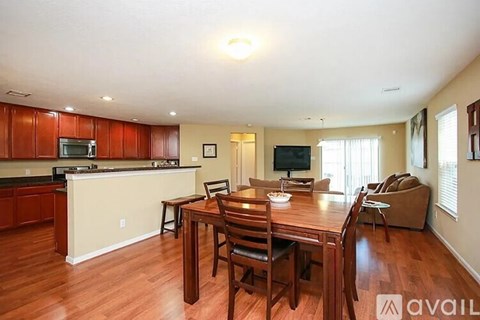 A kitchen with wooden cabinets and a dining table with chairs.
