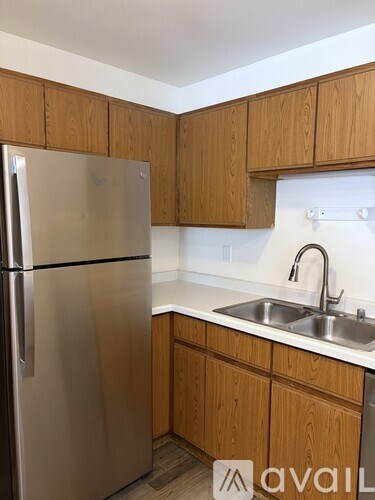 A kitchen with wooden cabinets and a stainless steel refrigerator.