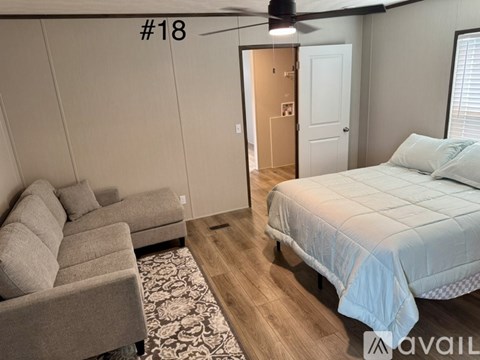 A bedroom with a bed, couch, and rug.