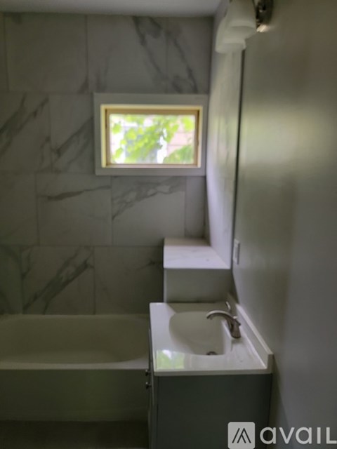 A bathroom with a tub, sink and window.