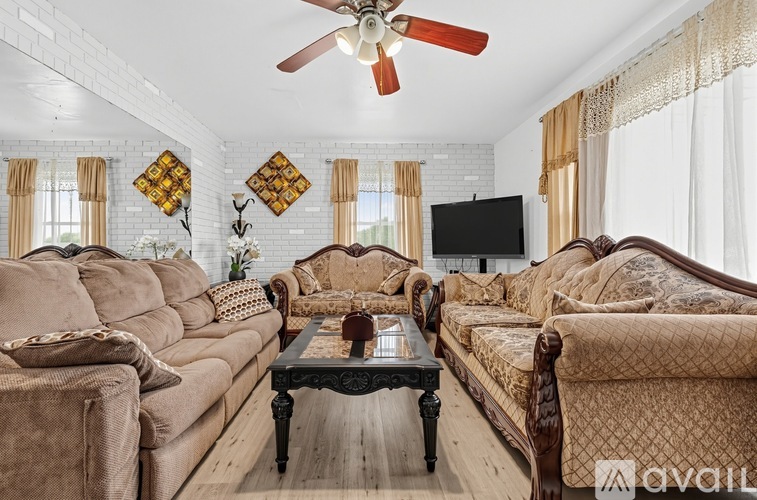 A living room with a brown sofa, a coffee table, and a ceiling fan.