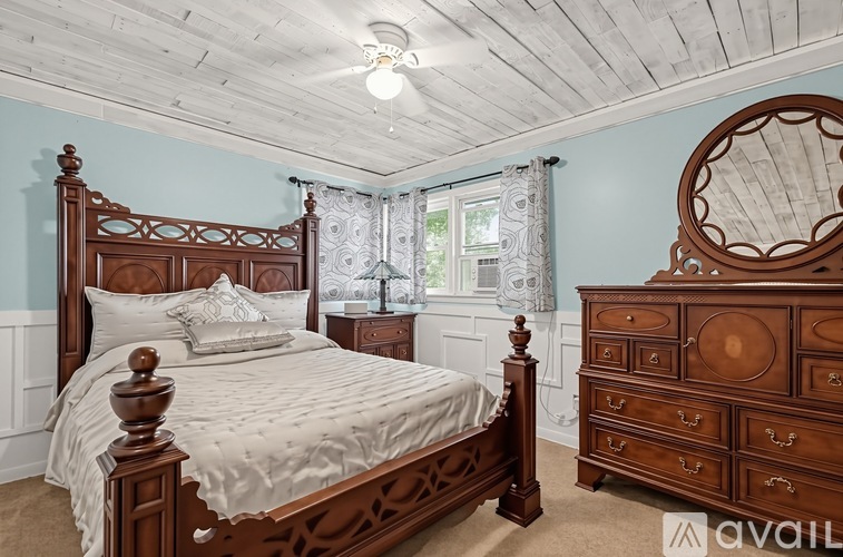 A bedroom with a large bed and a wooden dresser.
