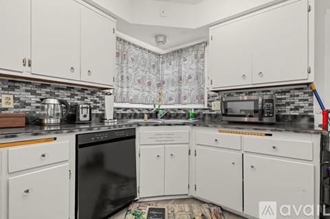 A kitchen with white cabinets and a black microwave.