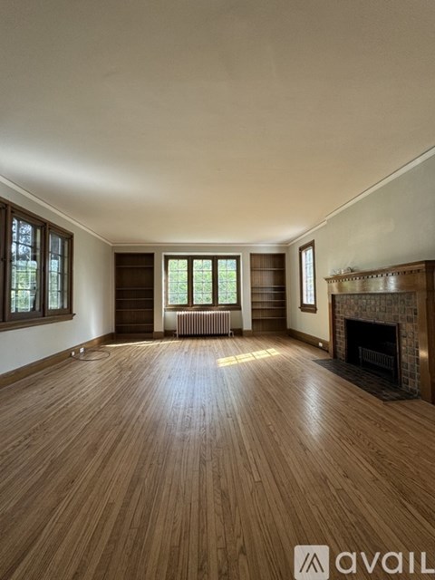 A spacious room with wooden flooring and a fireplace.