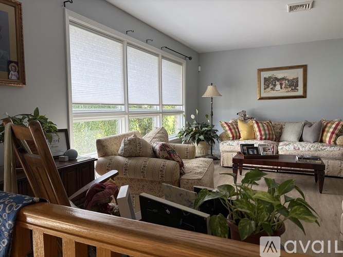A living room with a couch, chair, and potted plants.