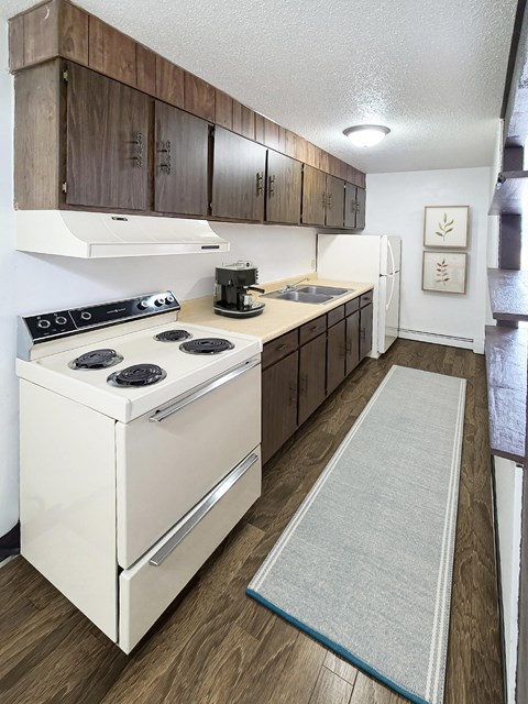 A kitchen with a white stove top oven and wooden cabinets.