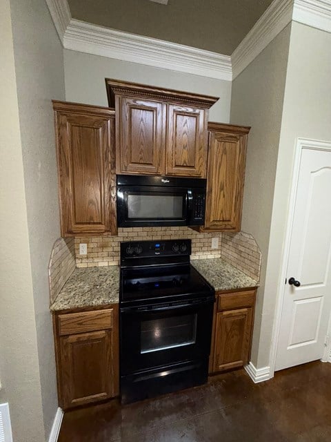 A kitchen with wooden cabinets and black appliances.
