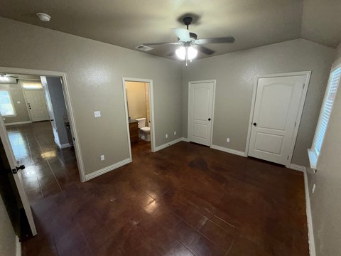 A room with a ceiling fan and wooden flooring.