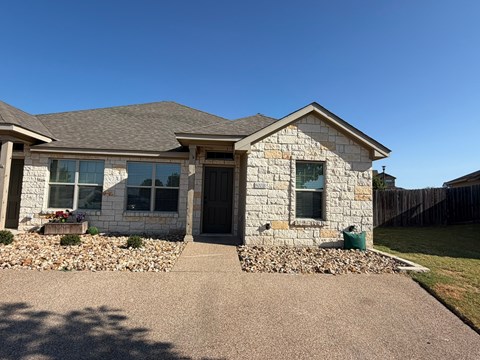 A house with a grey roof and stone exterior is shown.