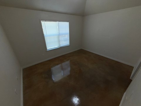 A room with a brown floor and a window letting in light.