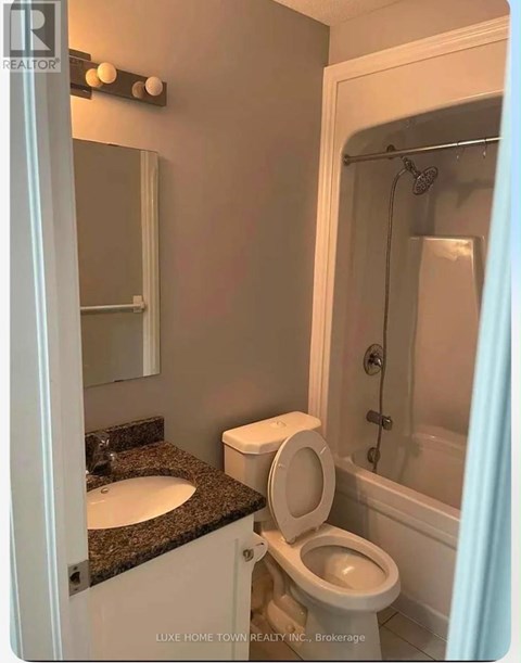 A white toilet is in a bathroom with a sink and mirror.