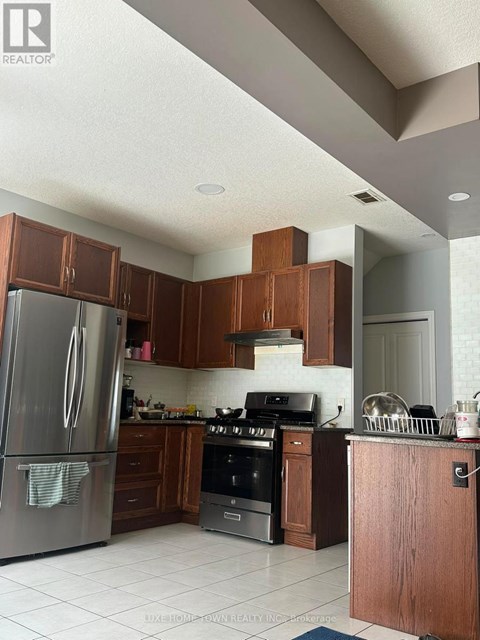 A kitchen with a refrigerator, oven, and cabinets.