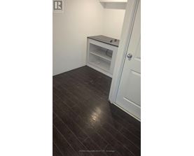 A white door is open to a room with a black floor and a white cabinet with a microwave on top.
