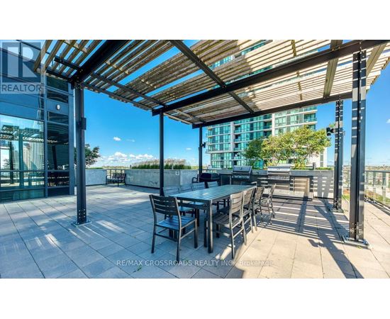 A patio with a table and chairs under a wooden roof.