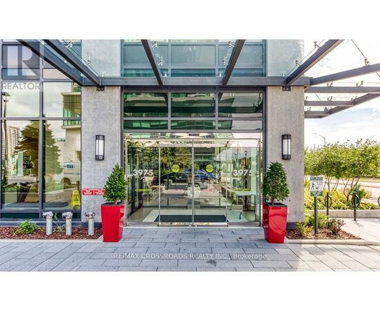 The front of a building with a glass door and two red planters on either side.