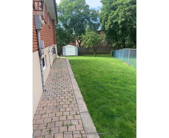 A backyard with a brick walkway leading to a white shed.