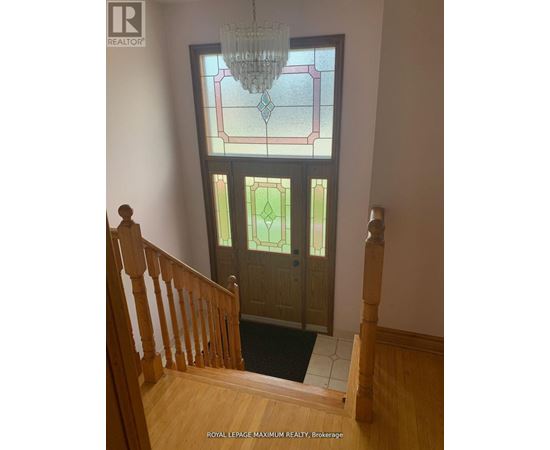 A stained glass window in a home with a wooden staircase.