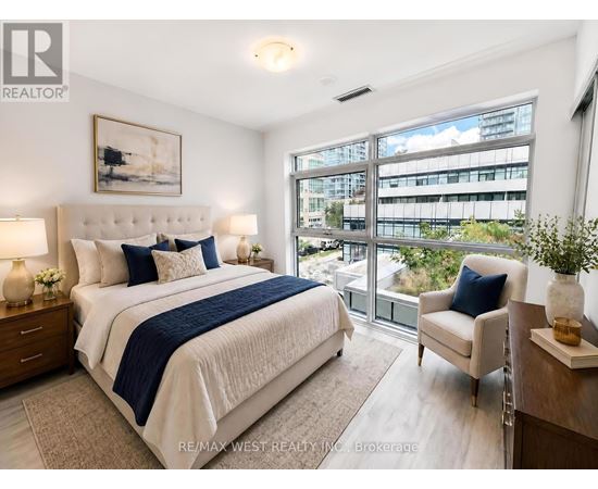 A bedroom with a large bed and a view of a cityscape through the window.